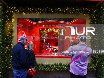 People take photos with their mobile devices of Macy's department store windows in New York, N.Y., on December 17, 2024. (