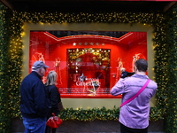 People take photos with their mobile devices of Macy's department store windows in New York, N.Y., on December 17, 2024. (