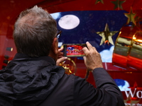 People take photos with their mobile devices of Macy's department store windows in New York, N.Y., on December 17, 2024. (