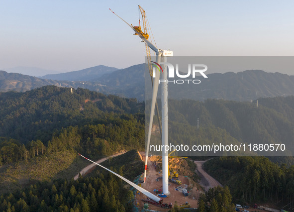 Workers lift the blades of a wind turbine at the construction site of the Guishushan Wind Farm project in Qingyun town of Congjiang county,...