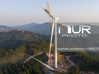 Workers lift the blades of a wind turbine at the construction site of the Guishushan Wind Farm project in Qingyun town of Congjiang county,...