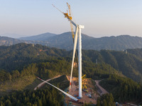 Workers lift the blades of a wind turbine at the construction site of the Guishushan Wind Farm project in Qingyun town of Congjiang county,...