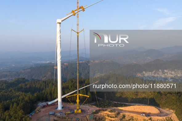 Workers lift the blades of a wind turbine at the construction site of the Guishushan Wind Farm project in Qingyun town of Congjiang county,...