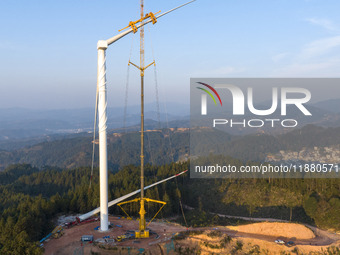 Workers lift the blades of a wind turbine at the construction site of the Guishushan Wind Farm project in Qingyun town of Congjiang county,...