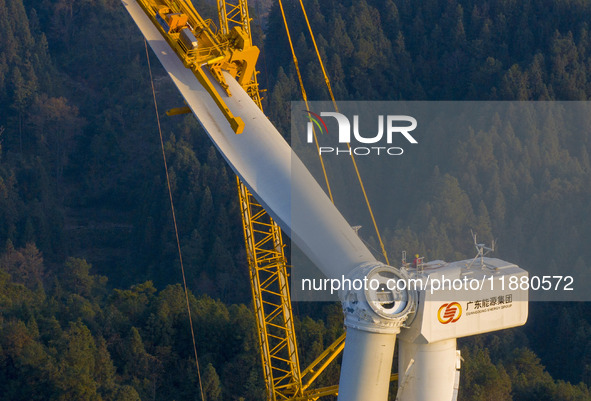 Workers lift the blades of a wind turbine at the construction site of the Guishushan Wind Farm project in Qingyun town of Congjiang county,...