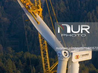 Workers lift the blades of a wind turbine at the construction site of the Guishushan Wind Farm project in Qingyun town of Congjiang county,...