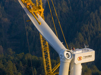 Workers lift the blades of a wind turbine at the construction site of the Guishushan Wind Farm project in Qingyun town of Congjiang county,...