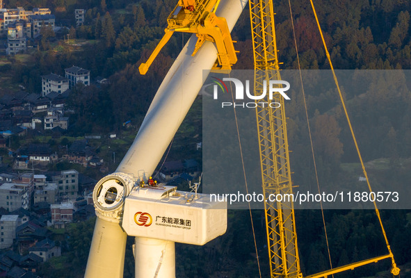 Workers lift the blades of a wind turbine at the construction site of the Guishushan Wind Farm project in Qingyun town of Congjiang county,...