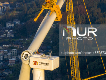 Workers lift the blades of a wind turbine at the construction site of the Guishushan Wind Farm project in Qingyun town of Congjiang county,...