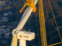 Workers lift the blades of a wind turbine at the construction site of the Guishushan Wind Farm project in Qingyun town of Congjiang county,...