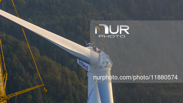 Workers lift the blades of a wind turbine at the construction site of the Guishushan Wind Farm project in Qingyun town of Congjiang county,...