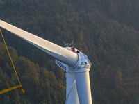 Workers lift the blades of a wind turbine at the construction site of the Guishushan Wind Farm project in Qingyun town of Congjiang county,...