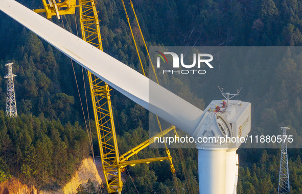 Workers lift the blades of a wind turbine at the construction site of the Guishushan Wind Farm project in Qingyun town of Congjiang county,...