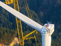 Workers lift the blades of a wind turbine at the construction site of the Guishushan Wind Farm project in Qingyun town of Congjiang county,...