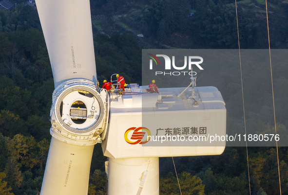 Workers lift the blades of a wind turbine at the construction site of the Guishushan Wind Farm project in Qingyun town of Congjiang county,...