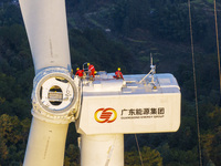 Workers lift the blades of a wind turbine at the construction site of the Guishushan Wind Farm project in Qingyun town of Congjiang county,...