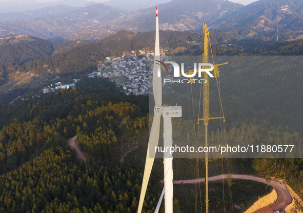 Workers lift the blades of a wind turbine at the construction site of the Guishushan Wind Farm project in Qingyun town of Congjiang county,...