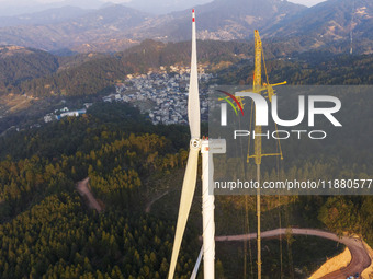 Workers lift the blades of a wind turbine at the construction site of the Guishushan Wind Farm project in Qingyun town of Congjiang county,...