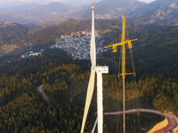 Workers lift the blades of a wind turbine at the construction site of the Guishushan Wind Farm project in Qingyun town of Congjiang county,...