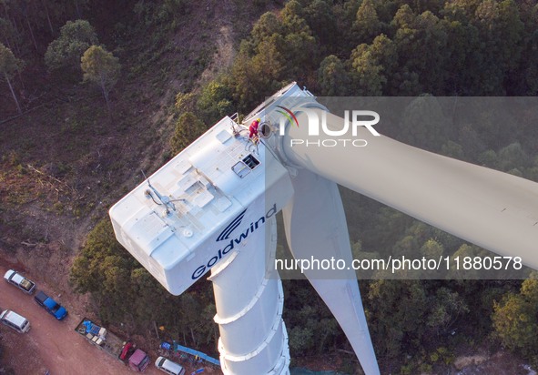 Workers lift the blades of a wind turbine at the construction site of the Guishushan Wind Farm project in Qingyun town of Congjiang county,...