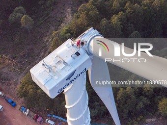 Workers lift the blades of a wind turbine at the construction site of the Guishushan Wind Farm project in Qingyun town of Congjiang county,...