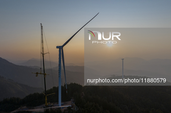 Workers lift the blades of a wind turbine at the construction site of the Guishushan Wind Farm project in Qingyun town of Congjiang county,...