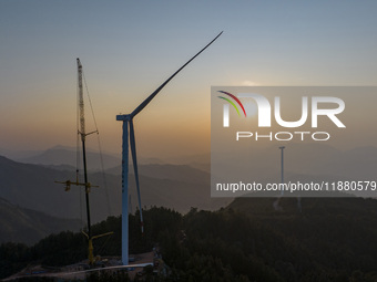 Workers lift the blades of a wind turbine at the construction site of the Guishushan Wind Farm project in Qingyun town of Congjiang county,...