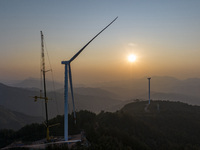 Workers lift the blades of a wind turbine at the construction site of the Guishushan Wind Farm project in Qingyun town of Congjiang county,...