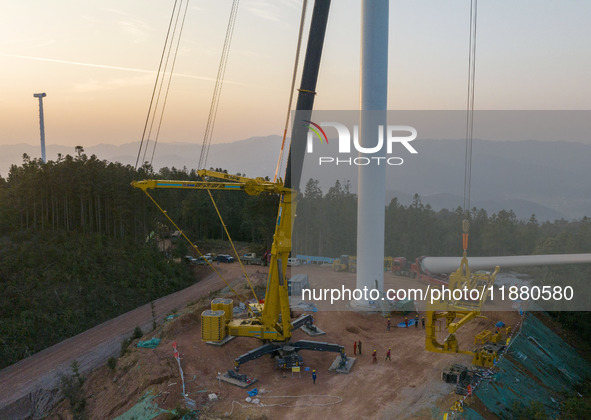 Workers lift the blades of a wind turbine at the construction site of the Guishushan Wind Farm project in Qingyun town of Congjiang county,...