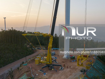 Workers lift the blades of a wind turbine at the construction site of the Guishushan Wind Farm project in Qingyun town of Congjiang county,...