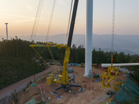 Workers lift the blades of a wind turbine at the construction site of the Guishushan Wind Farm project in Qingyun town of Congjiang county,...