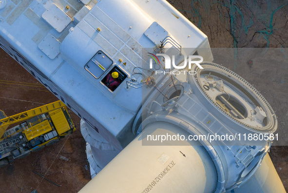 Workers lift the blades of a wind turbine at the construction site of the Guishushan Wind Farm project in Qingyun town of Congjiang county,...