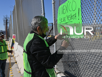 Angels Without Borders activist Sergio Tamai posts posters on a port of entry fence demanding respect for Mexico and its people during a dem...