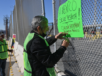 Angels Without Borders activist Sergio Tamai posts posters on a port of entry fence demanding respect for Mexico and its people during a dem...