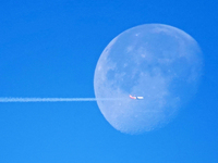 A passenger plane flies past the moon in Yantai, China, on December 19, 2024. (