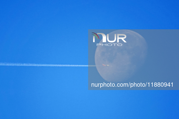 A passenger plane flies past the moon in Yantai, China, on December 19, 2024. 