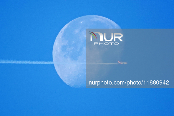 A passenger plane flies past the moon in Yantai, China, on December 19, 2024. 