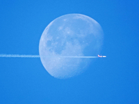 A passenger plane flies past the moon in Yantai, China, on December 19, 2024. (