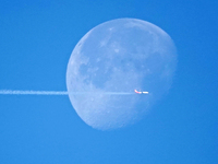 A passenger plane flies past the moon in Yantai, China, on December 19, 2024. (