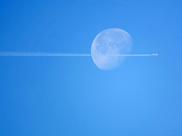 A passenger plane flies past the moon in Yantai, China, on December 19, 2024. (