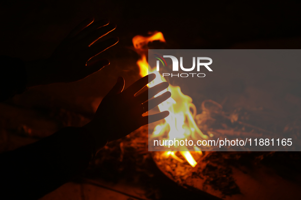 A person sits near a bonfire in Kathmandu, Nepal, on December 19, 2024, as the temperature drops, increasing the cold in the Nepali capital....