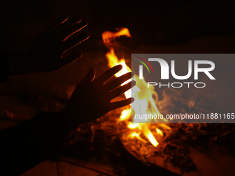 A person sits near a bonfire in Kathmandu, Nepal, on December 19, 2024, as the temperature drops, increasing the cold in the Nepali capital....