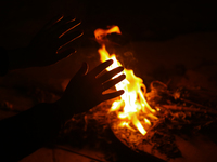 A person sits near a bonfire in Kathmandu, Nepal, on December 19, 2024, as the temperature drops, increasing the cold in the Nepali capital....