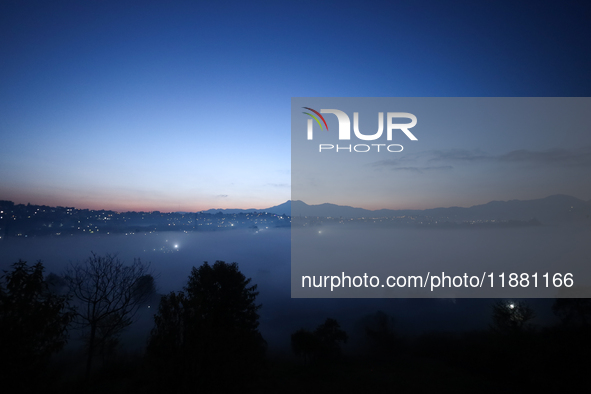 The sun rises behind the hills surrounding Kathmandu Valley as the cold fog covers the bowl-shaped valley in Kathmandu, Nepal, on December 1...