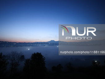 The sun rises behind the hills surrounding Kathmandu Valley as the cold fog covers the bowl-shaped valley in Kathmandu, Nepal, on December 1...