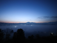 The sun rises behind the hills surrounding Kathmandu Valley as the cold fog covers the bowl-shaped valley in Kathmandu, Nepal, on December 1...