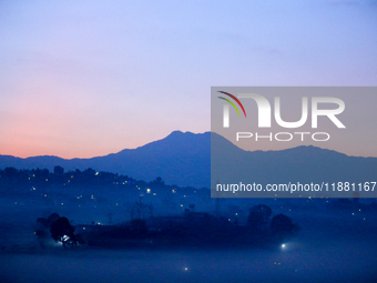 The sun rises behind the hills surrounding Kathmandu Valley as the cold fog covers the bowl-shaped valley in Kathmandu, Nepal, on December 1...