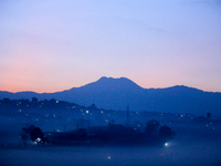 The sun rises behind the hills surrounding Kathmandu Valley as the cold fog covers the bowl-shaped valley in Kathmandu, Nepal, on December 1...