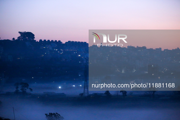 The sun rises behind the hills surrounding Kathmandu Valley as the cold fog covers the bowl-shaped valley in Kathmandu, Nepal, on December 1...