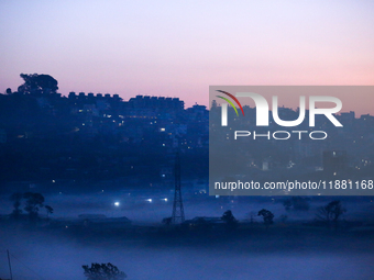 The sun rises behind the hills surrounding Kathmandu Valley as the cold fog covers the bowl-shaped valley in Kathmandu, Nepal, on December 1...